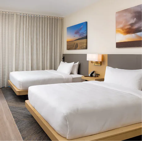 Hotel room with two beds and curtains.
