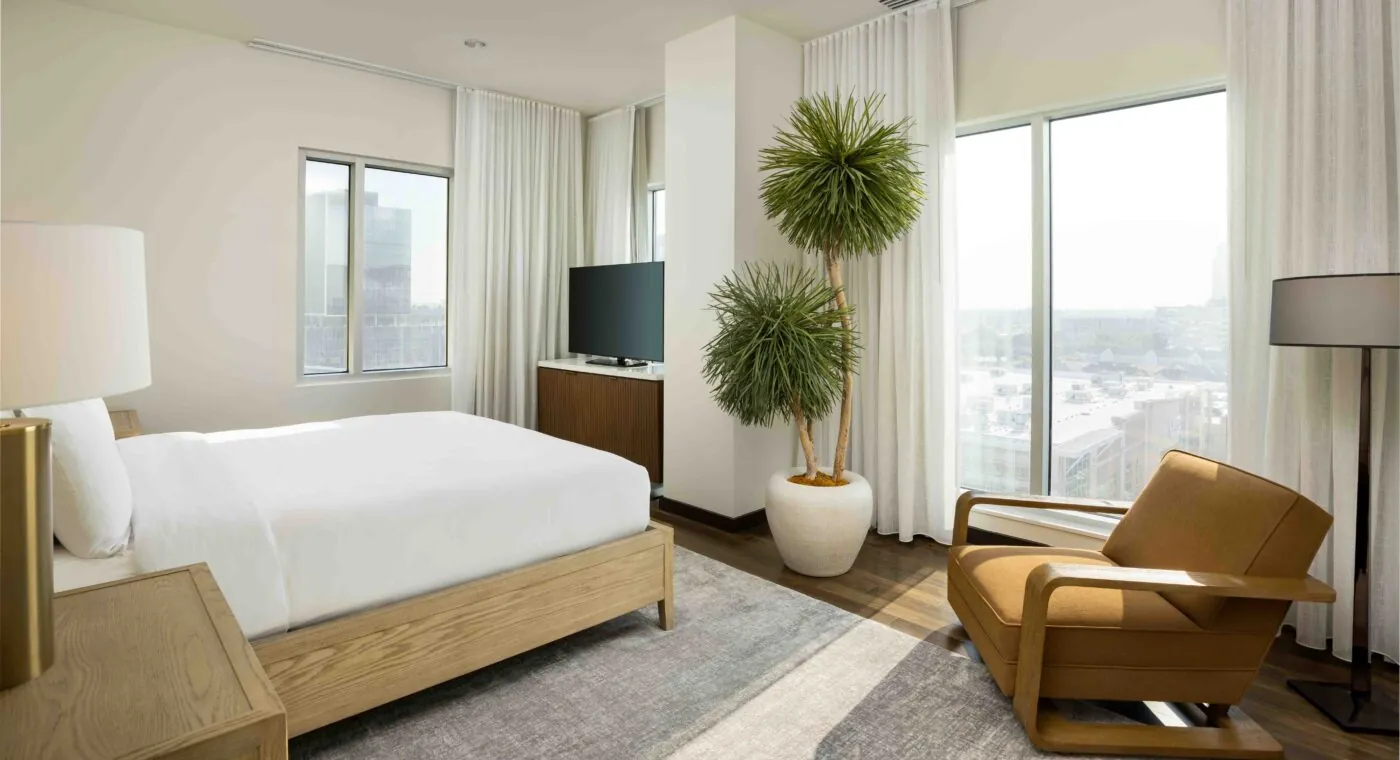 Hotel room with large bed and windows.