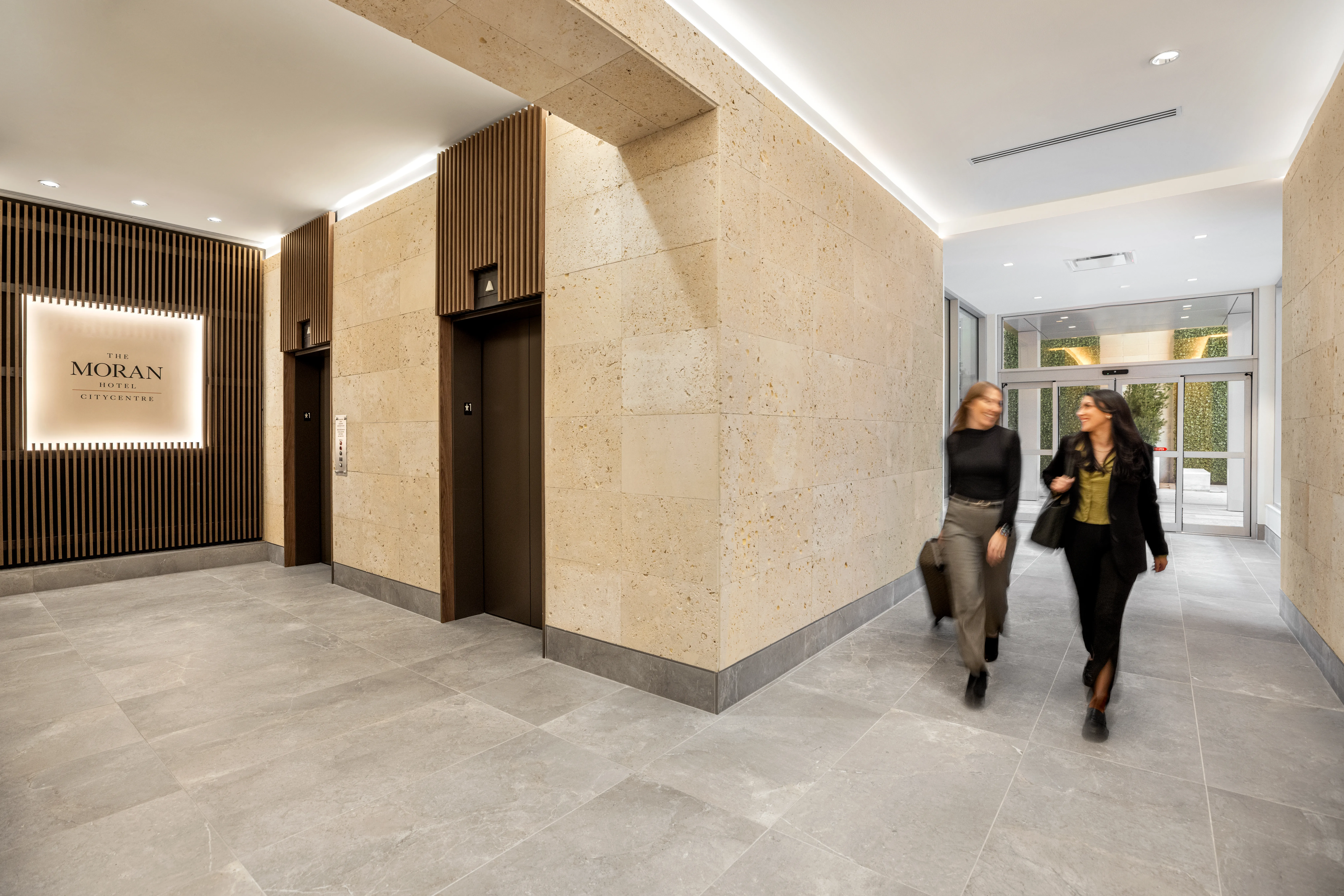Two women walking in hotel hallway.