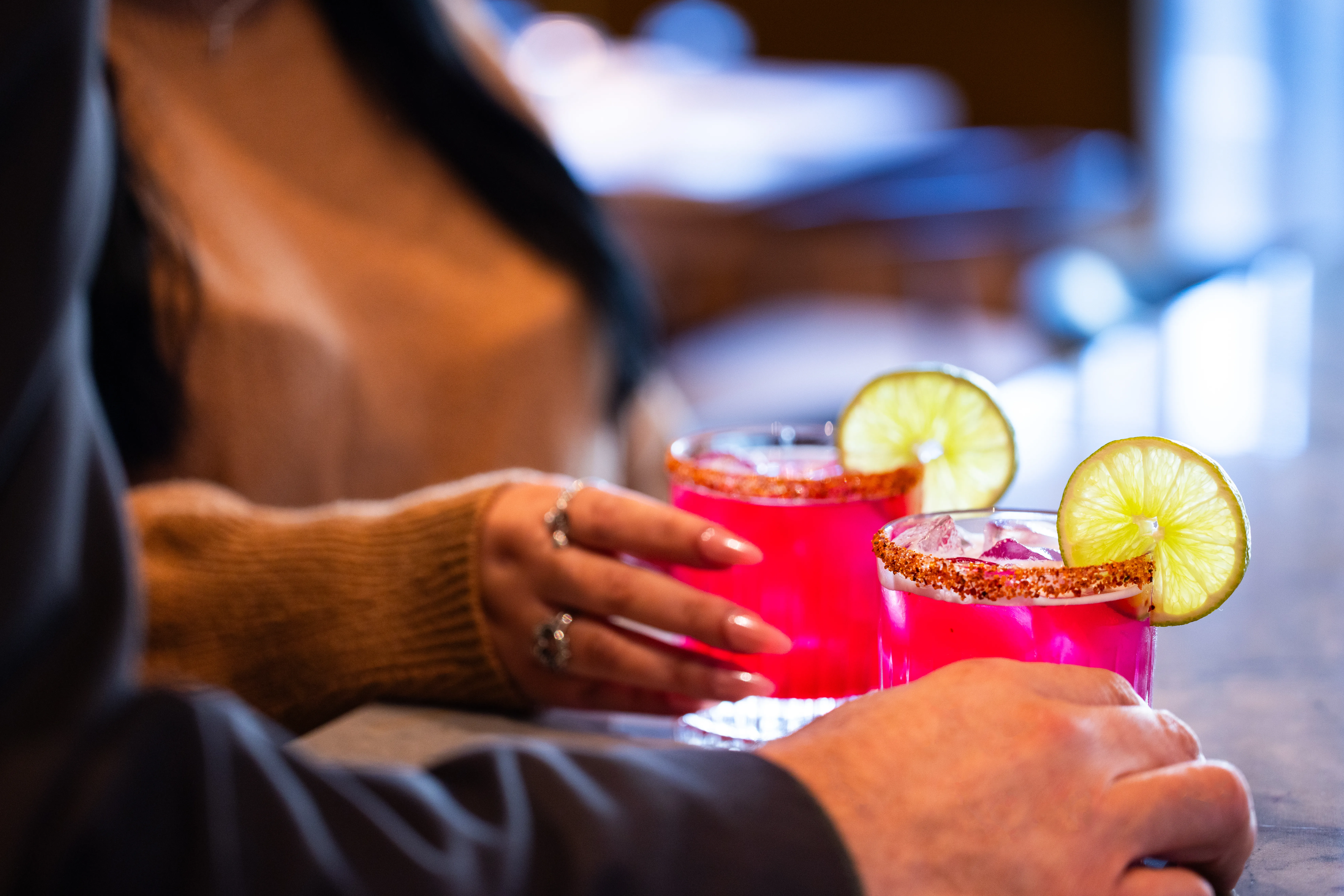 Bartender serving a red cocktail with lime garnish.