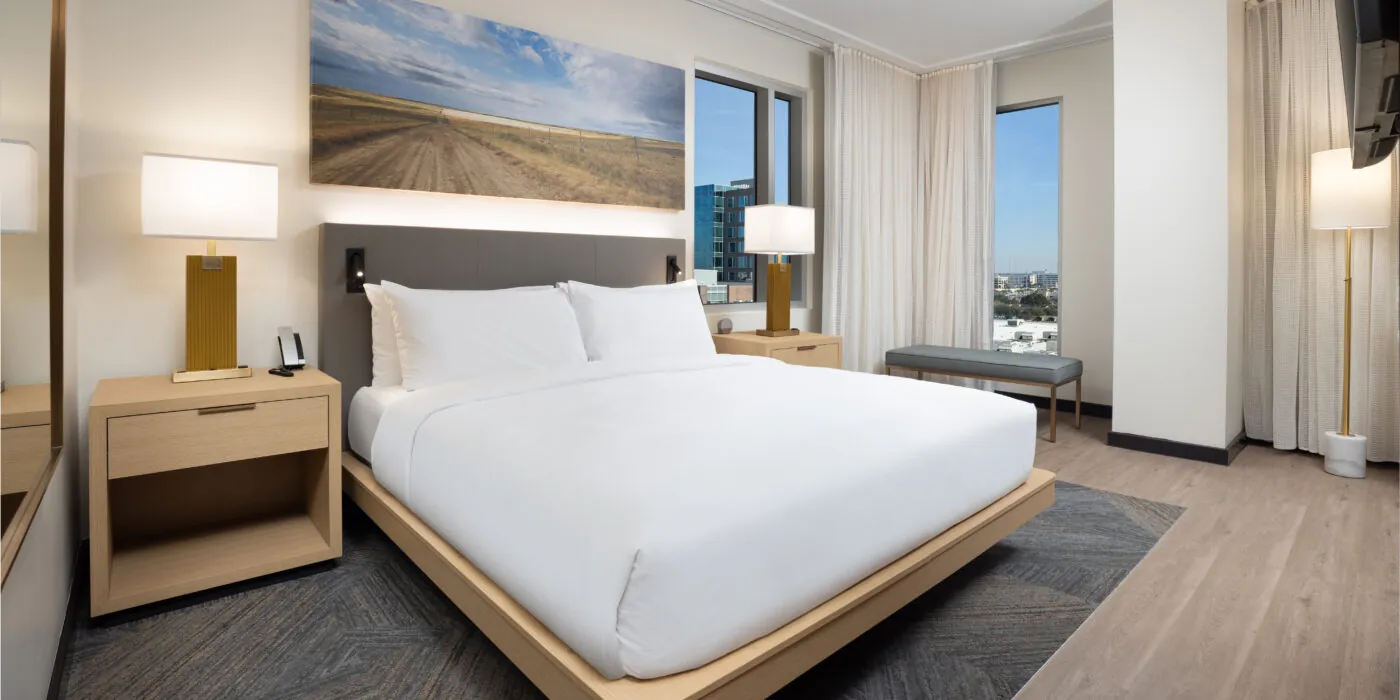 Hotel room with a large bed, wooden furnishings and natural light.