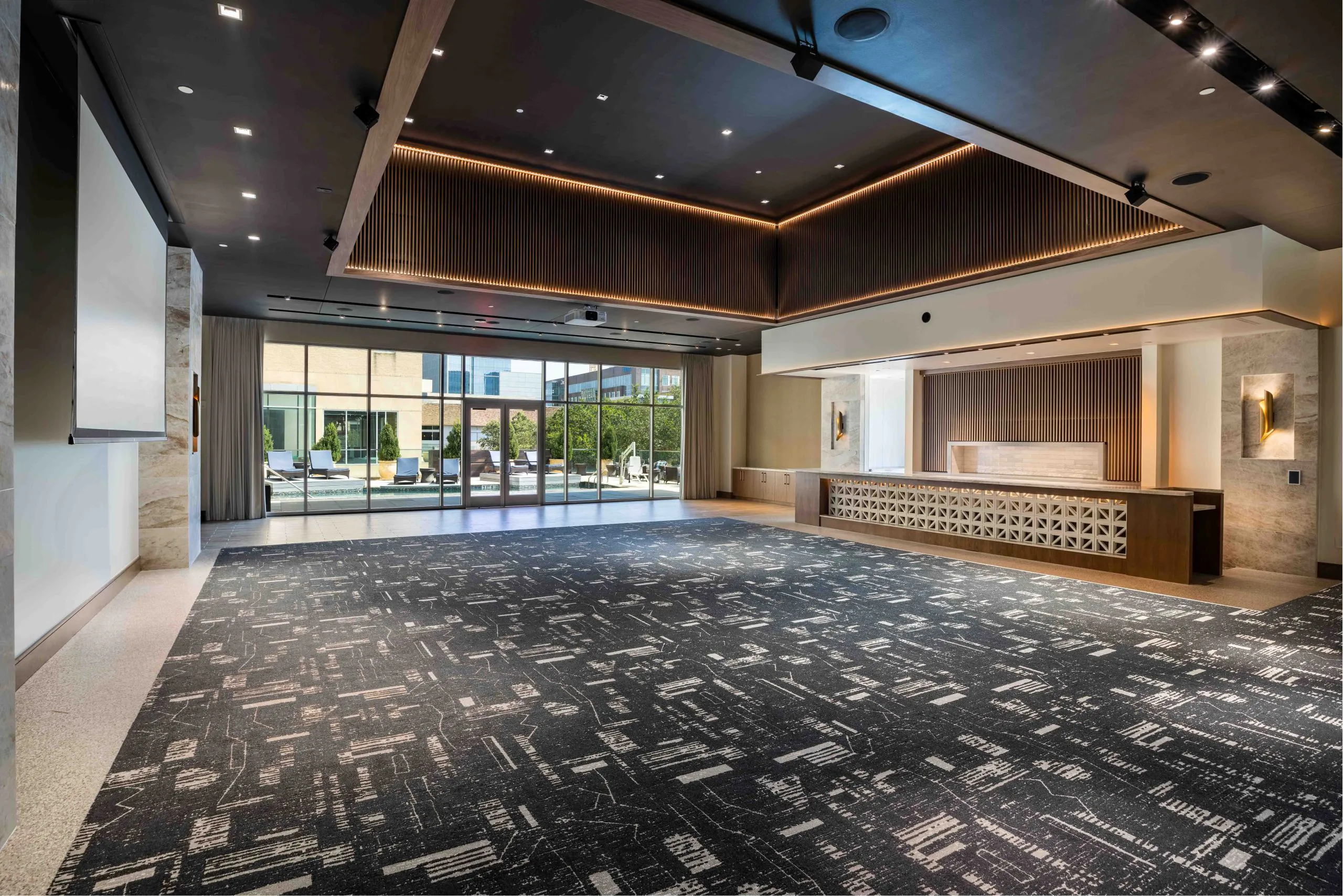 Large, empty ballroom with bar, windows, and a projector